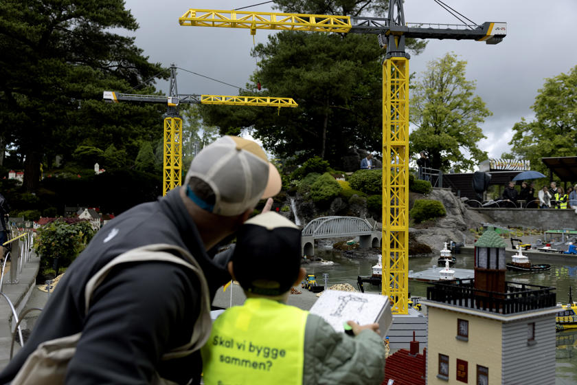 EN: Construction site for the Fehmarnbelt tunnel recreated using Lego bricks. In the foreground, a child stands with his father and controls a crane in the exhibition. // DE: Aus Legosteinen nachgebaute Baustelle für den Fehmarnbelt-Tunnel. Im Vordergrund steht ein Kind mit seinem Vater und steuert einen Kran in der Ausstellung. // DA: Byggeplads for Fehmarnbelt-tunnelen, bygget af Lego-klodser. I forgrunden står et barn sammen med sin far og styrer en kran i udstillingen.