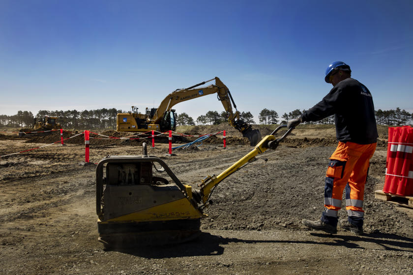 English: A worker compacts the ground with a vibrating plate. // Dansk: En arbejder komprimerer jorden med en rysteplade. // Deutsch: Ein Arbeiter verdichtet den Boden mit einer Rüttelplatte.