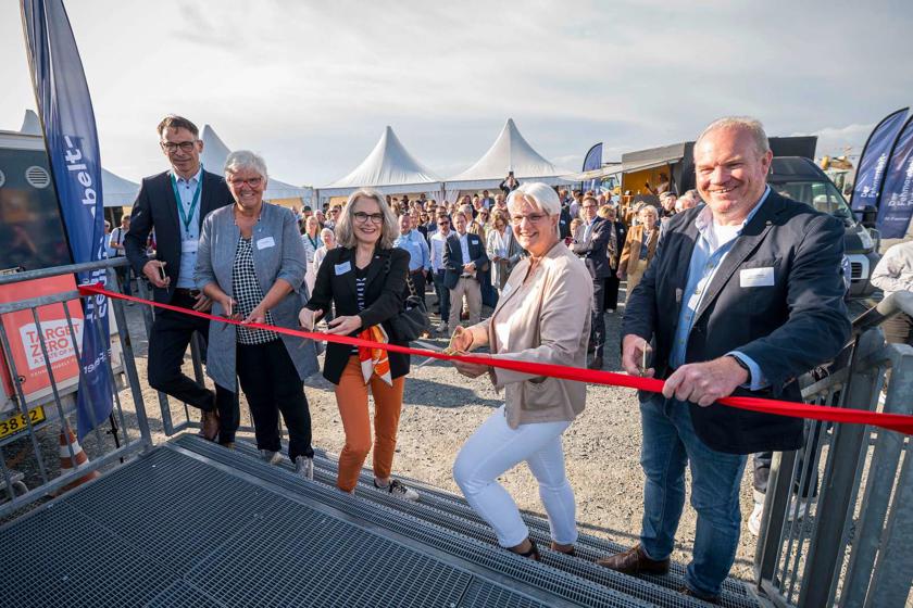 EN: Five people stand on the steps leading up to the new viewing point and cut a red ribbon. Around 200 guests can be seen in the background. // DE: 5 Personen stehen auf der Treppe zum neuen Aussichtspunkt und schneiden ein rotes Band durch. Im Hintergrund die rund 200 Gäste. // DK: 5 personer står på trappen til det nye udsigtspunkt og klipper et rødt bånd over. I baggrunden ses de ca. 200 gæster.