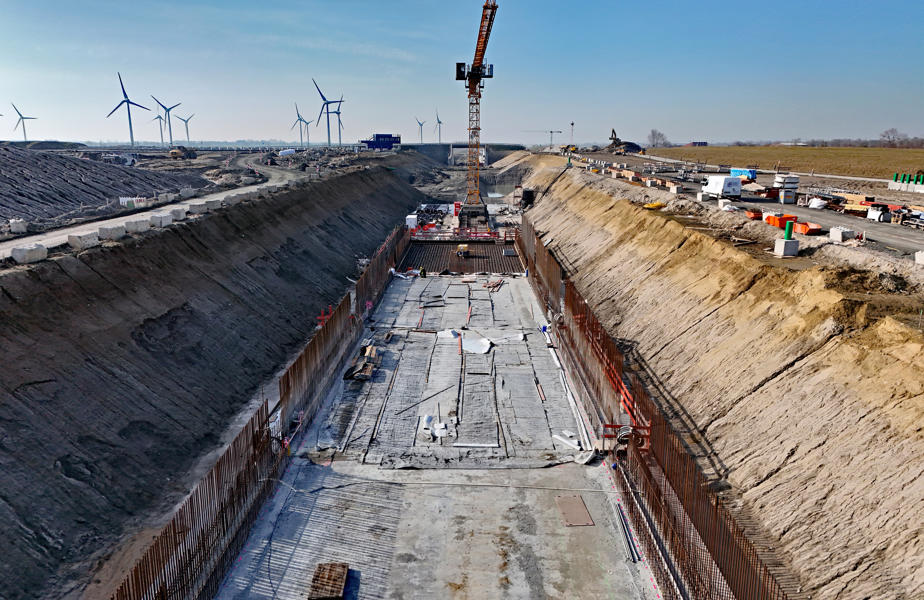In dem ausgehobenen Trog ist bereits die Betonsohle für die Bahntrasse betoniert. Auf beiden Seiten ist die Bewehrung für die späteren Wände zu sehen.