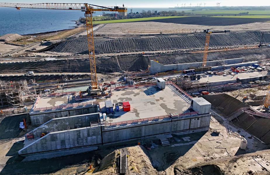 Im Vordergrund ist das Betriebsgebäude zu sehen: ein viereckiges Gebäude aus Beton. Daher entsteht aus Bewehrungsstahl und Beton die Tunneleinfahrt. Eine Außenwand ist angeschrägt, dort ist die Tunneleinfahrt.