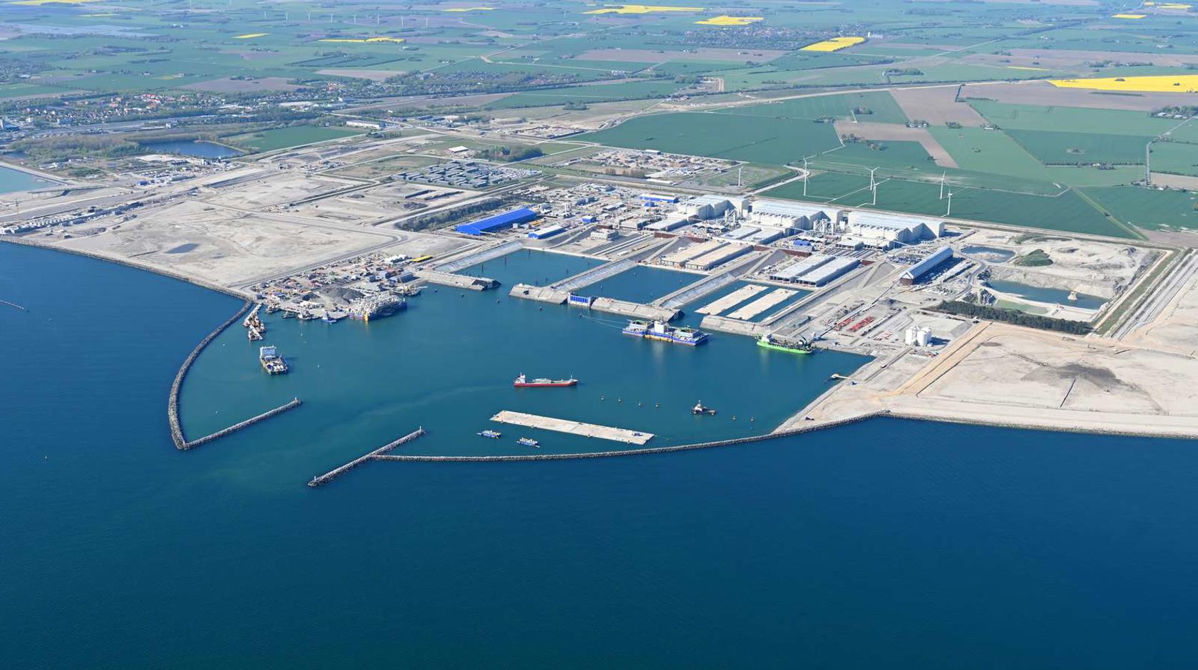 English: The Danish tunnel construction site. Several work vessels and a tunnel element are moored in the working harbour. // Dansk: Den danske tunnelbyggeplads. I arbejdshavnen ligger adskillige arbejdsskibe og en tunnelelement. // Deutsch: Die dänische Tunnelbaustelle. Im Arbeitshafen liegen etliche Arbeitsschiffe und ein Tunnelelement.
