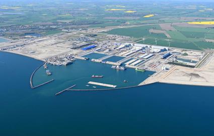 English: The Danish tunnel construction site. Several work vessels and a tunnel element are moored in the working harbour. // Dansk: Den danske tunnelbyggeplads. I arbejdshavnen ligger adskillige arbejdsskibe og en tunnelelement. // Deutsch: Die dänische Tunnelbaustelle. Im Arbeitshafen liegen etliche Arbeitsschiffe und ein Tunnelelement.