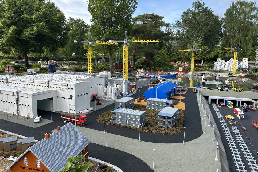 EN: Construction site for the Fehmarnbelt tunnel, recreated using Lego bricks. In the foreground is a white tunnel factory hall and the Danish tunnel portal. // DE: Aus Legosteinen nachgebaute Baustelle für den Fehmarnbelt-Tunnel. Hier im Vordergrund eine weiße Tunnelfabrikhalle und das dänische Tunnelportal. // DA: Byggeplads for Fehmarnbelt-tunnelen, bygget af Lego-klodser. Her i forgrunden ses en hvid tunnelfabrikhal og den danske tunnelportal.