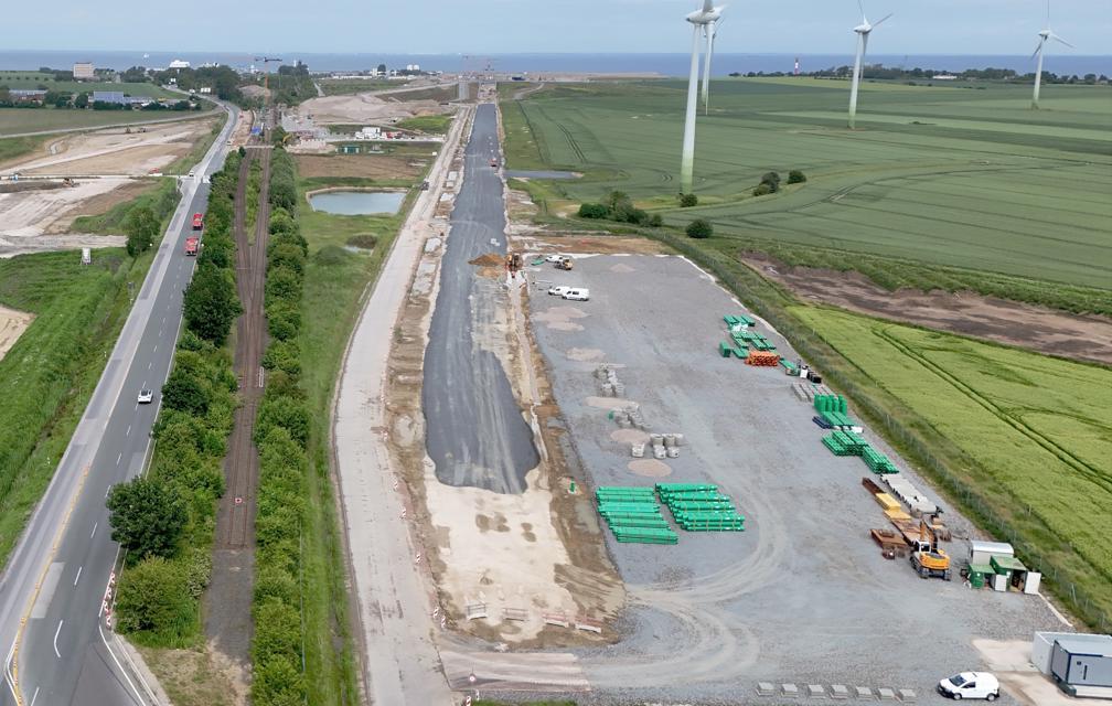 Das Luftbild zeigt in der Mitte die von Süden in Richtung Tunneleinfahrt verlaufende Bahntrasse. Deutlich zu erkennen, dass auf einem Großteil der Strecke bereits eine erste graue Schotterschicht aufgebracht worden ist.