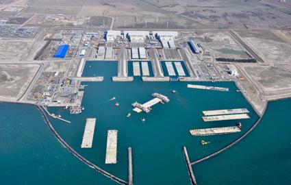 The Danish tunnel construction site. Work vessels and tunnel elements are moored in the working harbour. You can see the three large white halls where the tunnel elements are produced.