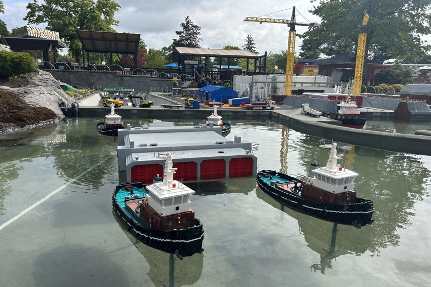 EN: Construction site for the Fehmarnbelt tunnel, recreated using Lego bricks. In the foreground is a tunnel element being pulled through the water by four tugboats. // DE: Aus Legosteinen nachgebaute Baustelle für den Fehmarnbelt-Tunnel. Hier im Vordergrund ein Tunnelelement, das von vier Schleppern auf dem Wasser gezogen wird. // DA: Byggeplads for Femern Bælt-tunnelen, bygget af Lego-klodser. Her i forgrunden ses en tunnelelement, der trækkes på vandet af fire slæbebåde.
